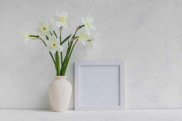 istock Mockup with a white frame and white daffodils in a vase 905163686