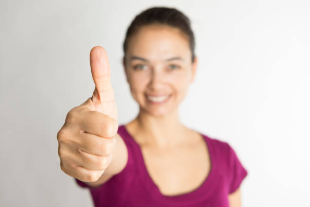 Happy woman gesturing thumbs up, white background.