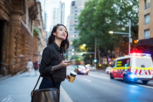 Asian woman waiting for an uber and drinking coffee