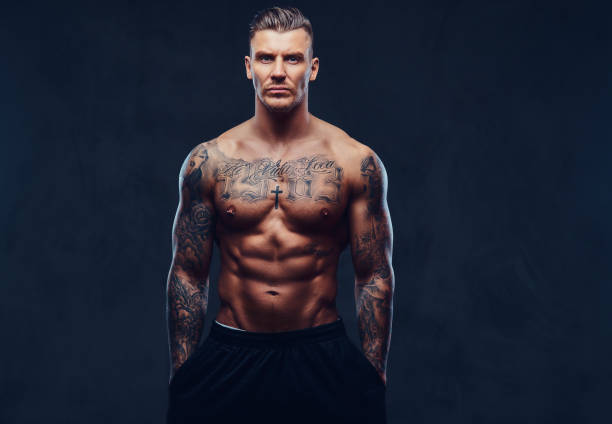 istock A muscular tattooed man over dark background. 905184004