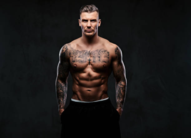 istock A muscular tattooed man on a dark background. 905184124
