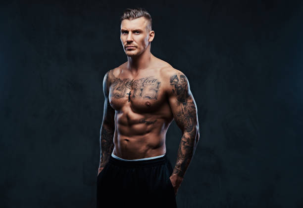 istock A muscular tattooed man on a dark background. 905184268