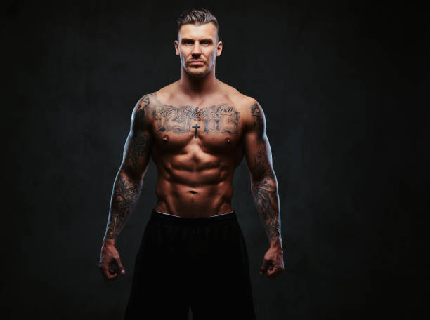 istock A muscular tattooed man on a dark background. 905185438