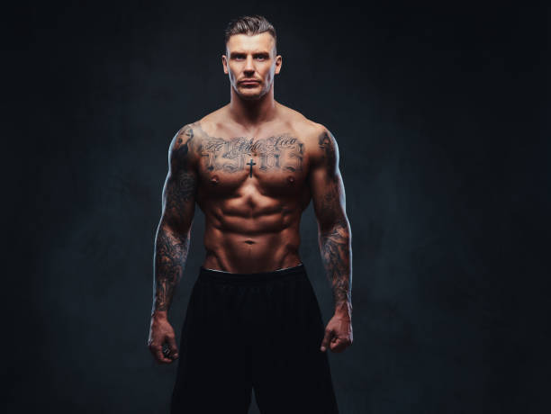 istock A muscular tattooed man on a dark background. 905185616
