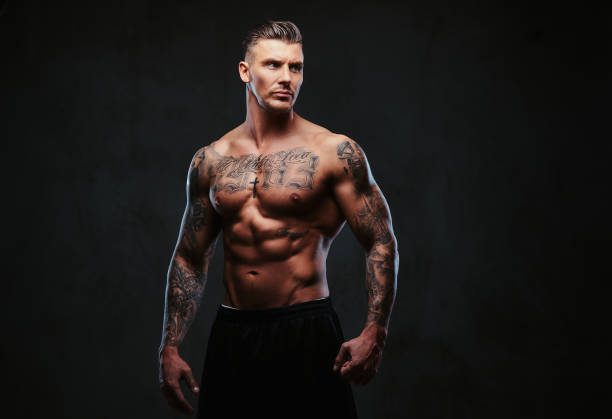 istock A muscular tattooed man on a dark background. 905185908
