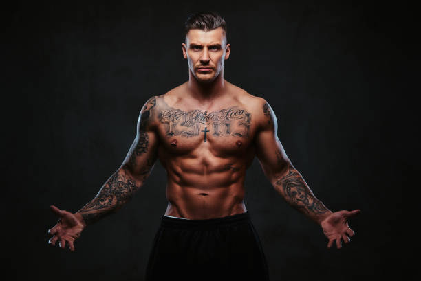 istock A muscular tattooed man on a dark background. 905186410