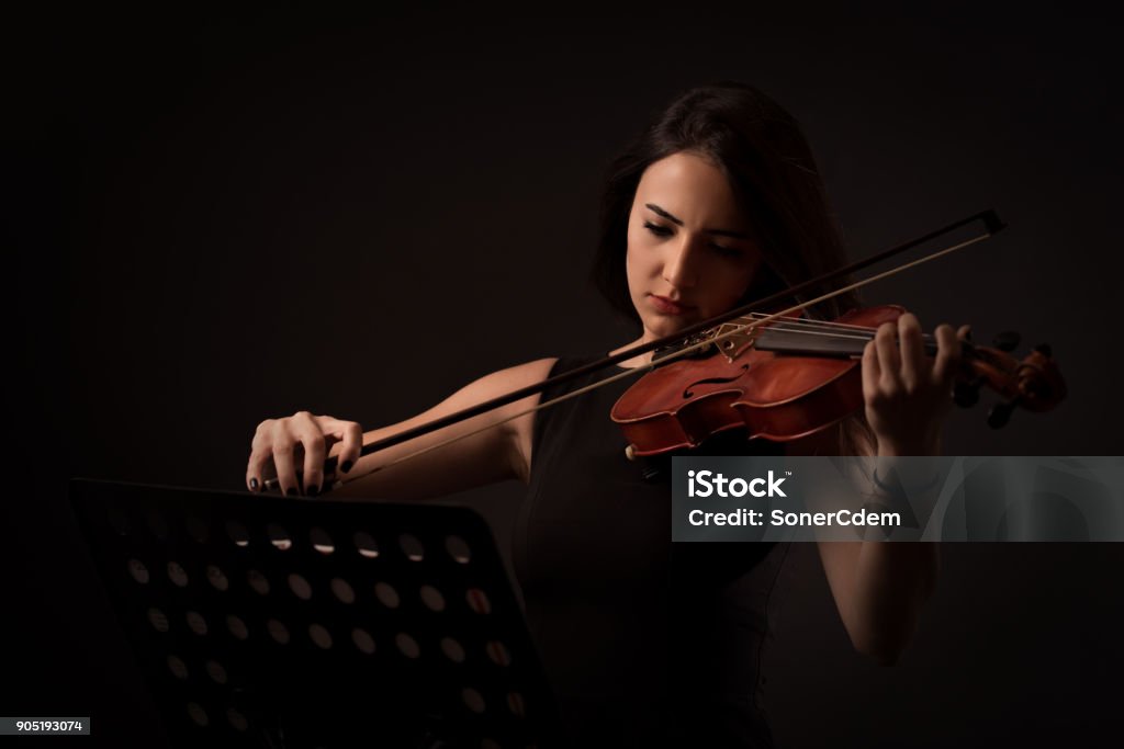 Hermosa mujer joven tocando un violín sobre fondo negro - Foto de stock de Violinista libre de derechos