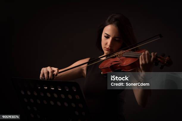 Hermosa Mujer Joven Tocando Un Violín Sobre Fondo Negro Foto de stock y más banco de imágenes de Violinista