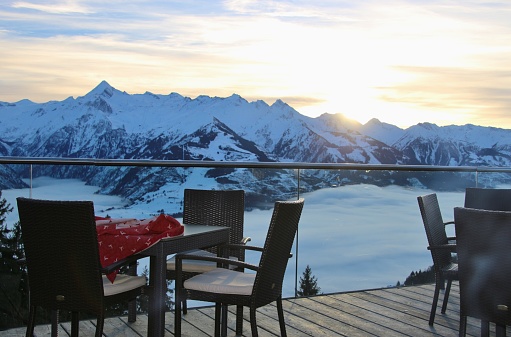 Chairs on a terrace of a cafe in the mountains and view of the Hohe Tauern mountain range. Zell am See, Austria.