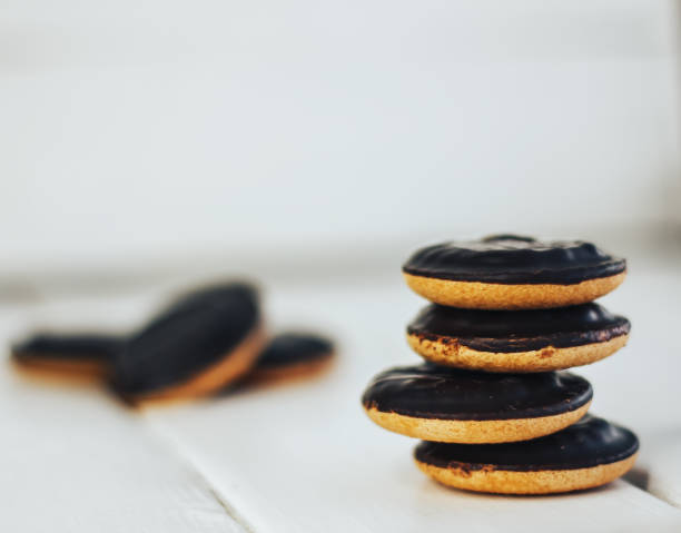 istock Cookie stack on a white wooden background. Round biscuits in chocolate glaze. Stands on each other 905220484