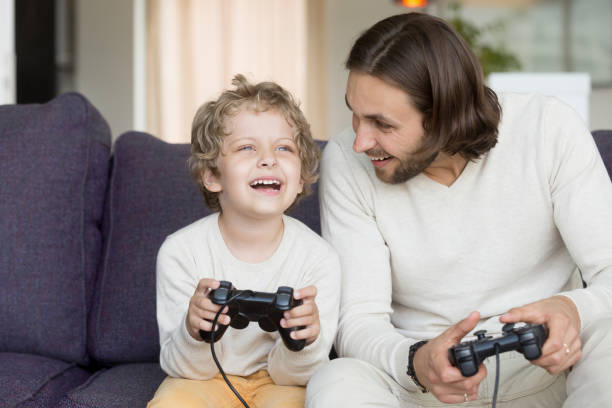 istock Father playing video games with son having fun holding controllers 905222736