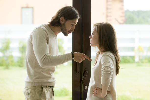 Young couple arguing at home, man pointing finger blaming woman Unhappy young couple arguing standing at house door, angry husband pointing at wife blaming her of problems, conflicts in marriage, bad relationships, man and woman having quarrel or disagreement girlfriend stock pictures, royalty-free photos & images
