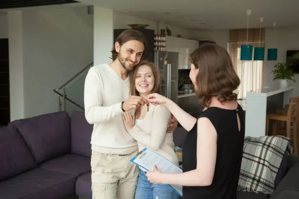 Photo of Happy young couple renters getting keys of new rental home