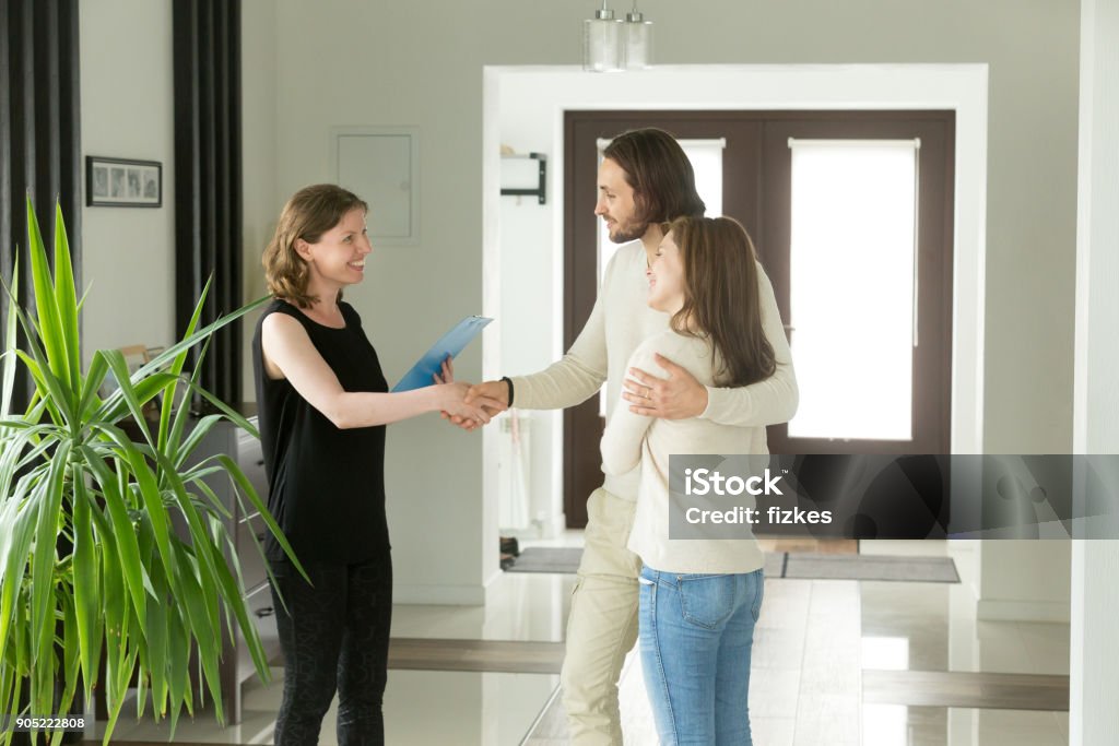 Freundlichen Makler und junges Paar Händeschütteln stehend im Flur - Lizenzfrei Wohnung Stock-Foto