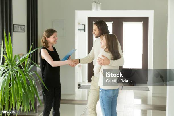 Freundlichen Makler Und Junges Paar Händeschütteln Stehend Im Flur Stockfoto und mehr Bilder von Wohnung