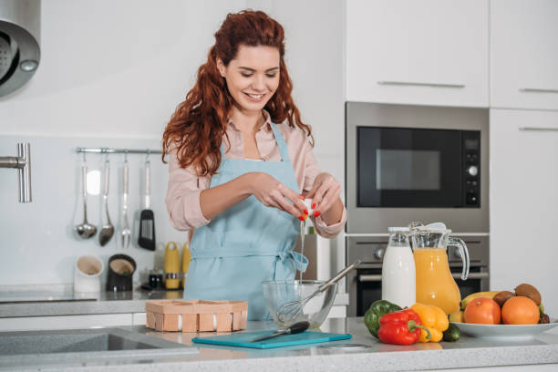 istock happy woman pouring egg into glass bowl 905231040