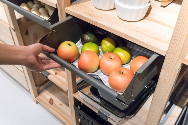 Hand pulling metal kitchen drawer filled with fake apples for display. Detail of furniture for home organizer. stock photo