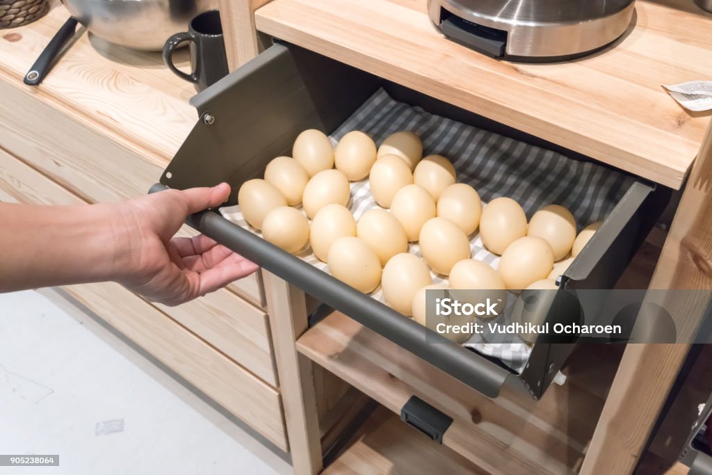 Hand pulling metal kitchen drawer filled with fake eggs for display. Detail of furniture for home organizer. Kitchen Stock Photo