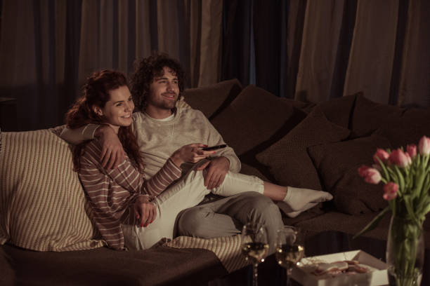 istock happy couple watching tv on sofa in evening 905241640