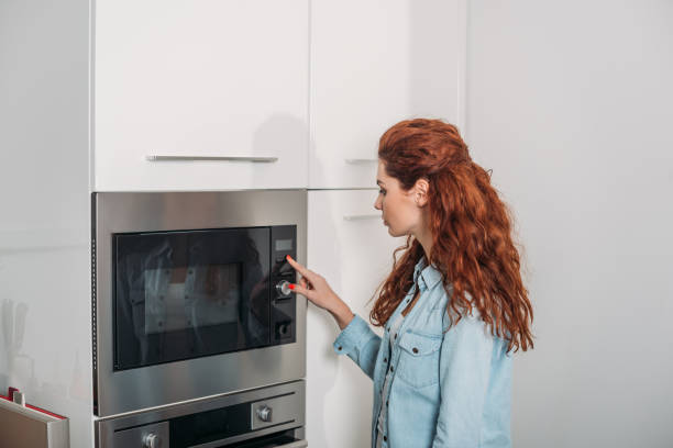 istock attractive woman turning on oven in kitchen 905241690