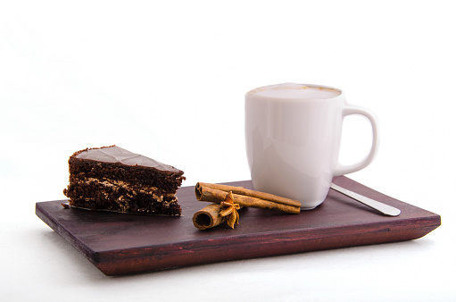 cup of coffee on a tray and cake with cinnamon and anise on a white background