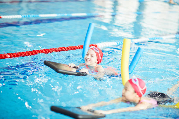 Easy swimming Two schoolgirls in swimwear and special swim devices learning to swim leisure facilities stock pictures, royalty-free photos & images