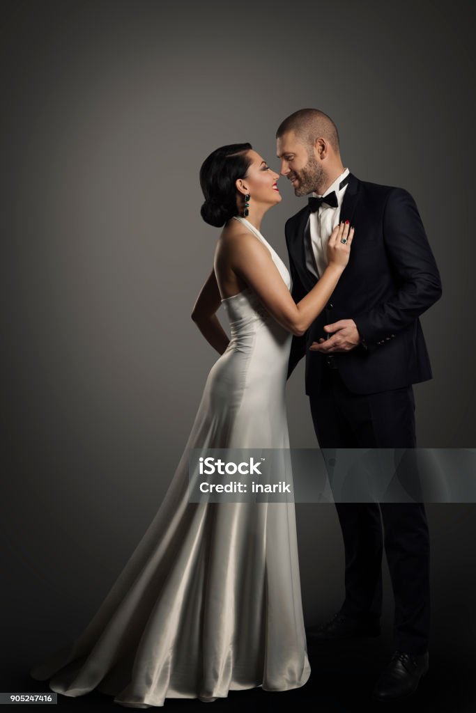 Retro Couple, Well Dressed Woman in Long White Dress, Elegant Man in Black Suit Retro Couple, Well Dressed Woman in Long White Dress and Elegant Man in Black Suit, Studio Full Length Portrait over black background Couple - Relationship Stock Photo