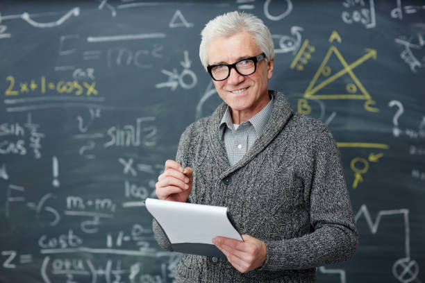 Teacher with document Grey-haired teacher in eyeglasses standing by blackboard with written formulae trigonometry stock pictures, royalty-free photos & images