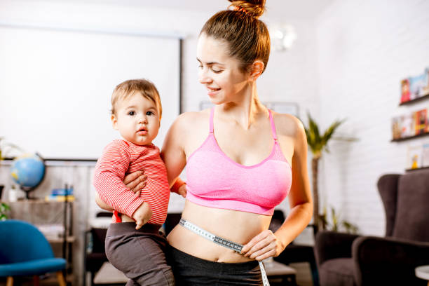 mother measuring her waist - mother exercising baby dieting imagens e fotografias de stock