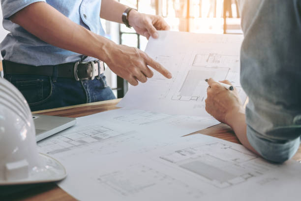 istock Image of engineer or architectural project, Close up of Architects engineer's hands drawing plan on BluePrint and discussing to partner with Engineering tools on workplace, Construction concept 905274452