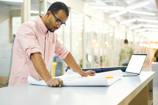 istock Skilled handsome male architect preparing planning for modern city district construction brainstorming using laptop computer with mock up screen and wireless connection to internet in office indoor 905280442