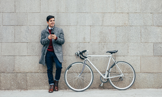 Elegant man with a bicycle using a smart phone in the city.