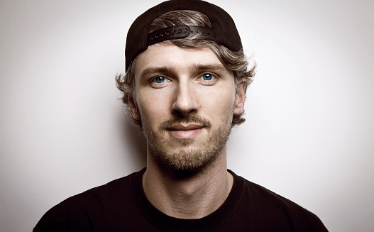 Young man with long curly hair in a baseball cap