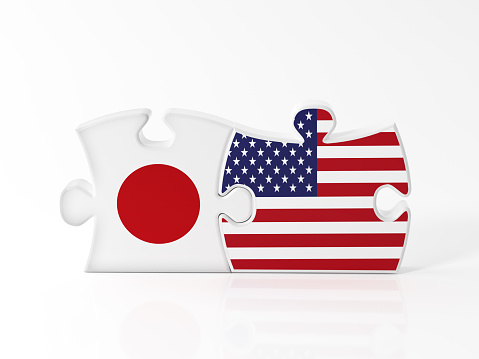 Jigsaw puzzle pieces textured with Japanese and American flags on white. Horizontal composition with copy space. Clipping path is included.