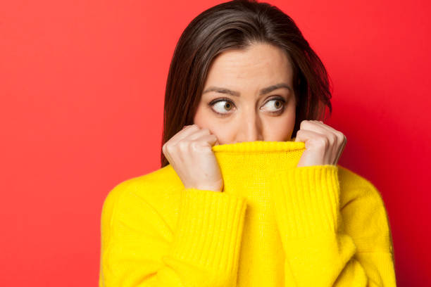 beautiful affraid woman in a yellow sweater on a red background - affraid imagens e fotografias de stock