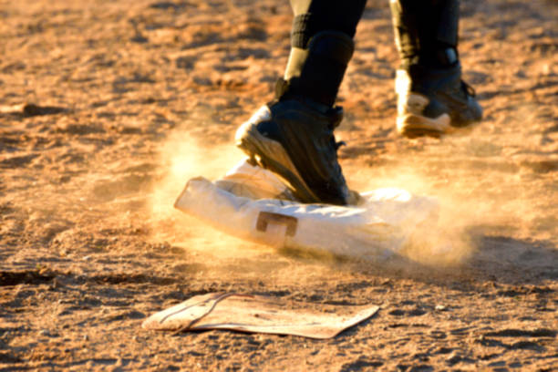 man running across dusty baseball base blurred background - base runner imagens e fotografias de stock