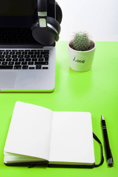 open notepad on a green surface with an open laptop - spiral notebook audio imagens e fotografias de stock