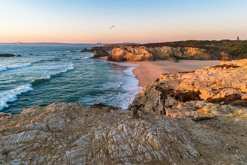 Puesta de sol en la playa con rocas en Porto Côvo en Alentejo, Portugal photo