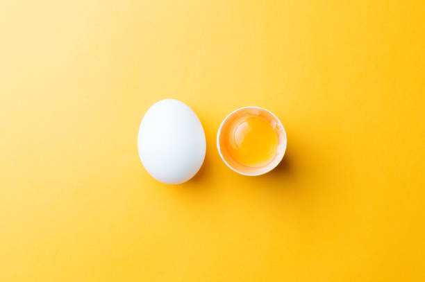 白い卵と背景が黄色の卵の黄身。topview - 卵 ストックフォトと画像