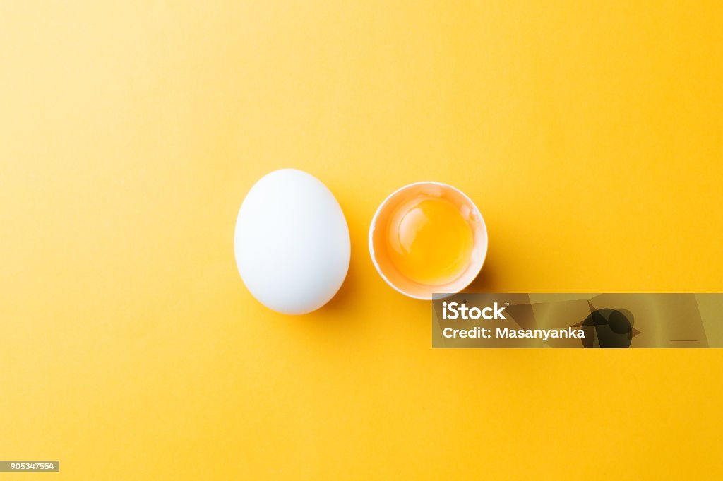 Vita ägg och äggula på gul bakgrund. topview - Royaltyfri Djurägg Bildbanksbilder