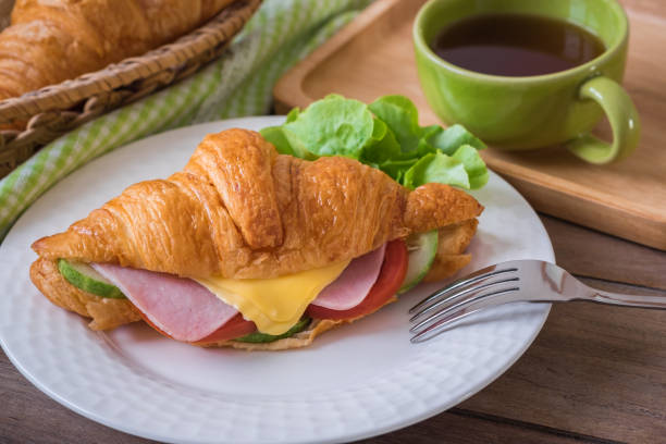 istock Croissant with ham, cheese on white plate and coffee cup 905347974