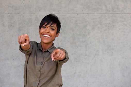 Portrait of cheerful young black woman pointing fingers with copy space