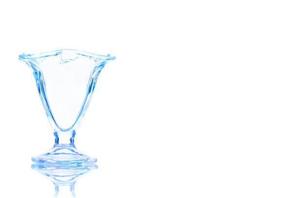 An empty glass dessert bowl toned in blue colorisolated on a white background. Place for your text.
