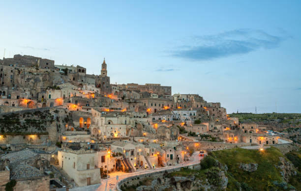 Cityscape of Sassi di Matera at dusk, Basilicata Italy Matera old town at dusk illuminated with warm street lights. matera stock pictures, royalty-free photos & images