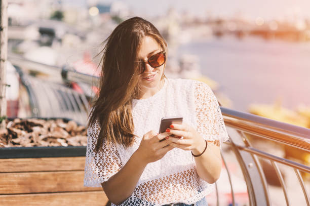 istock Girl holding mobile smartphone the hands on sunset background, soft focus 905352408