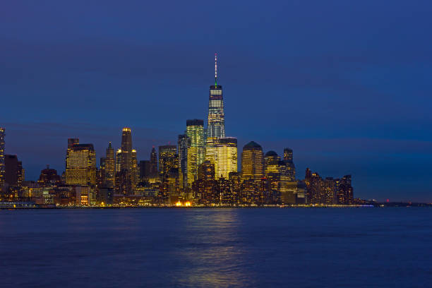 Low Manhattan skyline at night with reflection in Hudson River.