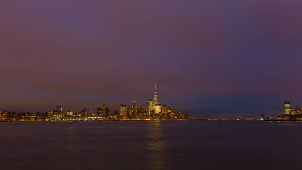 Low Manhattan skyline at night with reflection in Hudson River.