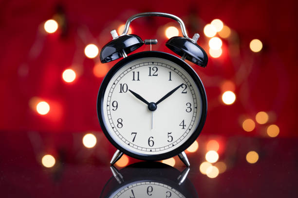 istock Alarm clock with party decoration light bokeh in the background using as time or wake up after party 905357914