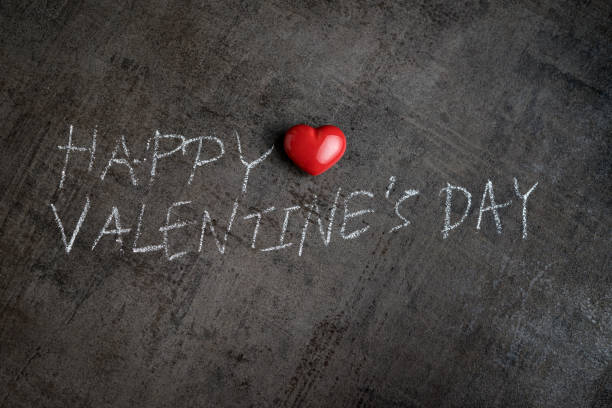 istock Handwriting with white chalk on cement wall Happy Valentine's day with red heart shape 905358094
