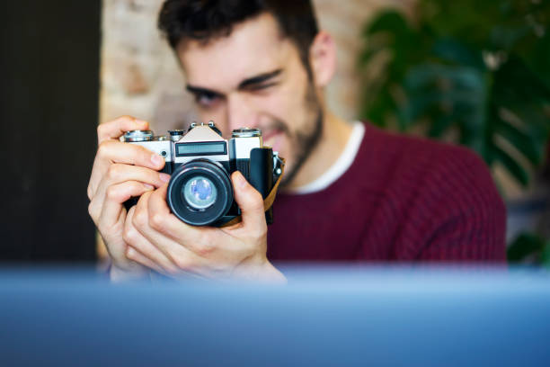 istock Selective focus on man's hands holding vintage camera with modern lense.Portrait of blurred professional photographer making photos. Blurred copy space area for your advertising text message 905358424